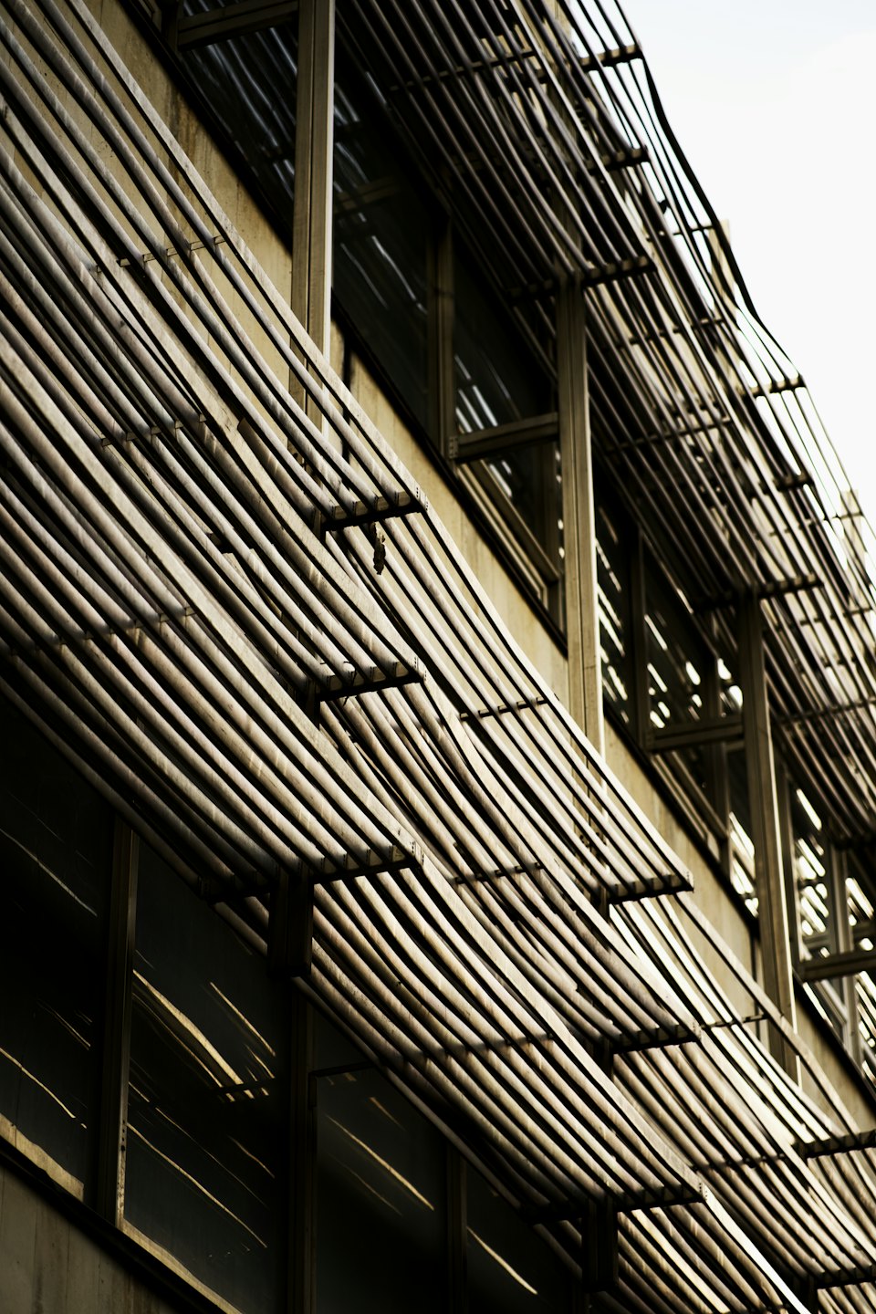 Fachada de edificio moderno con parasoles de madera creando sombras geométricas.
