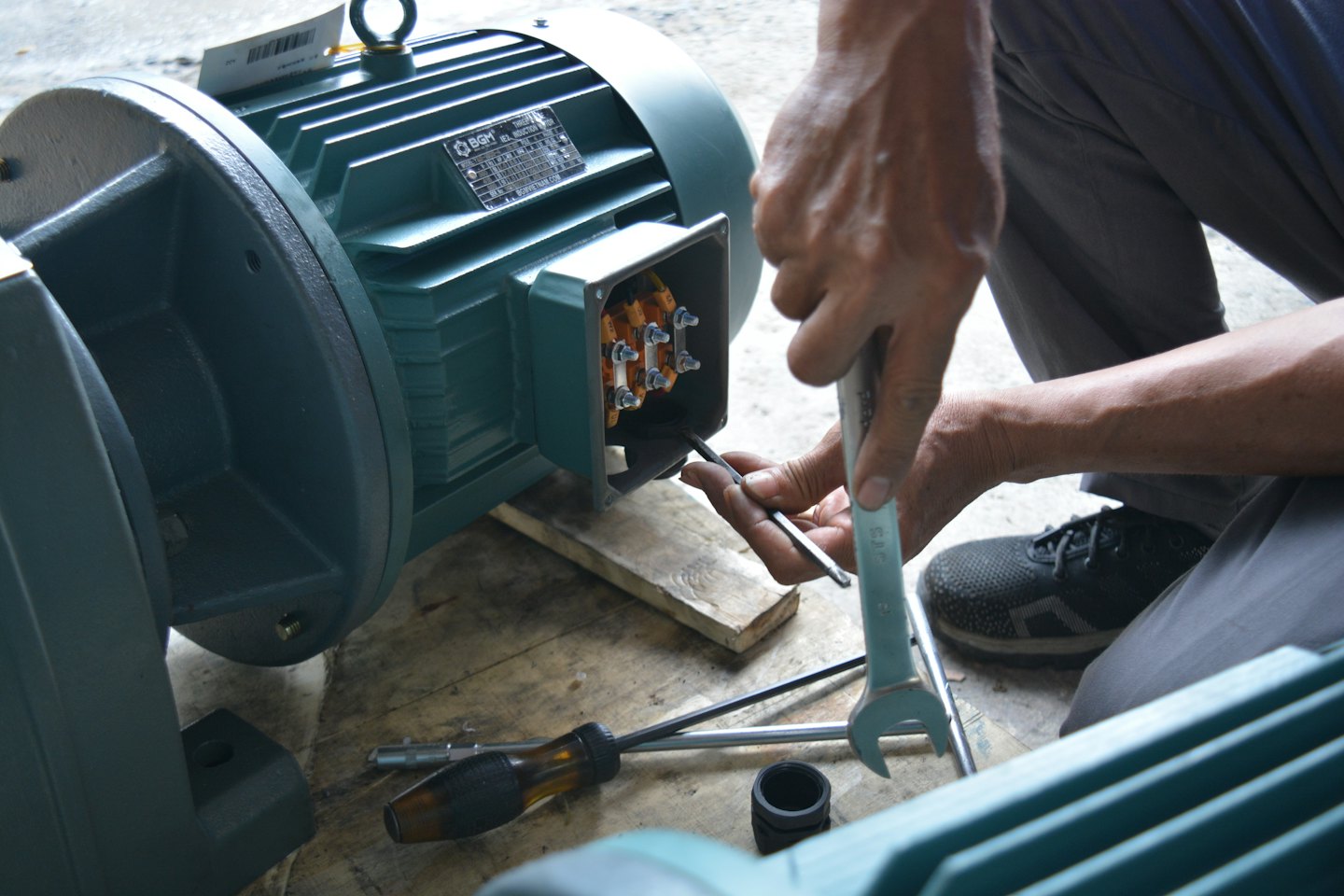 Manos de técnico conectando cables en un motor eléctrico industrial.