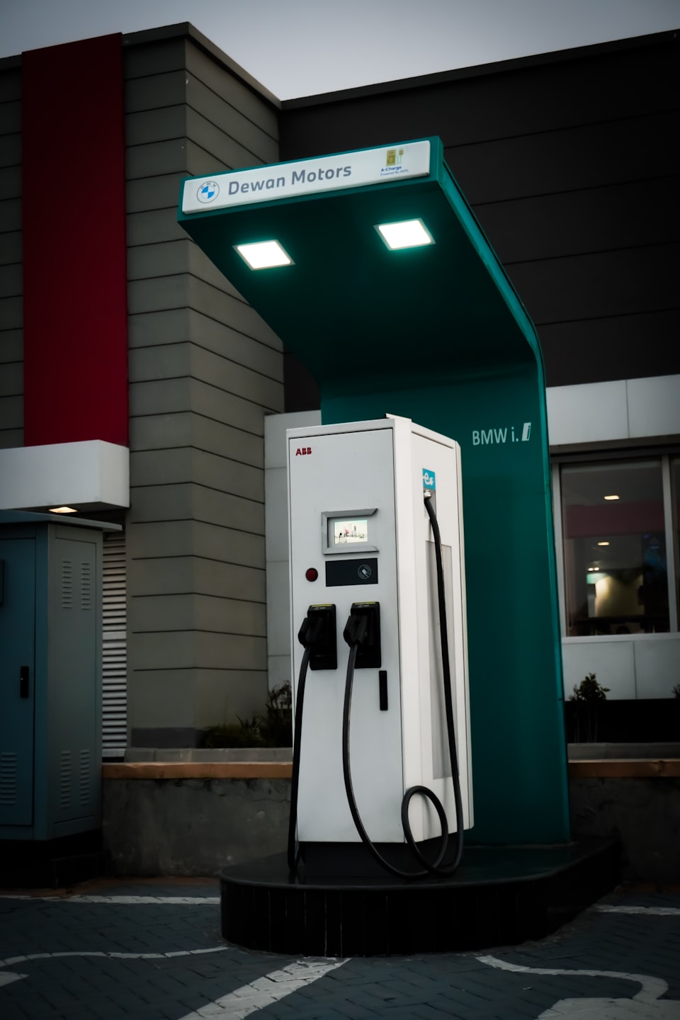 Estación de carga de vehículos eléctricos al aire libre frente a un edificio moderno.
